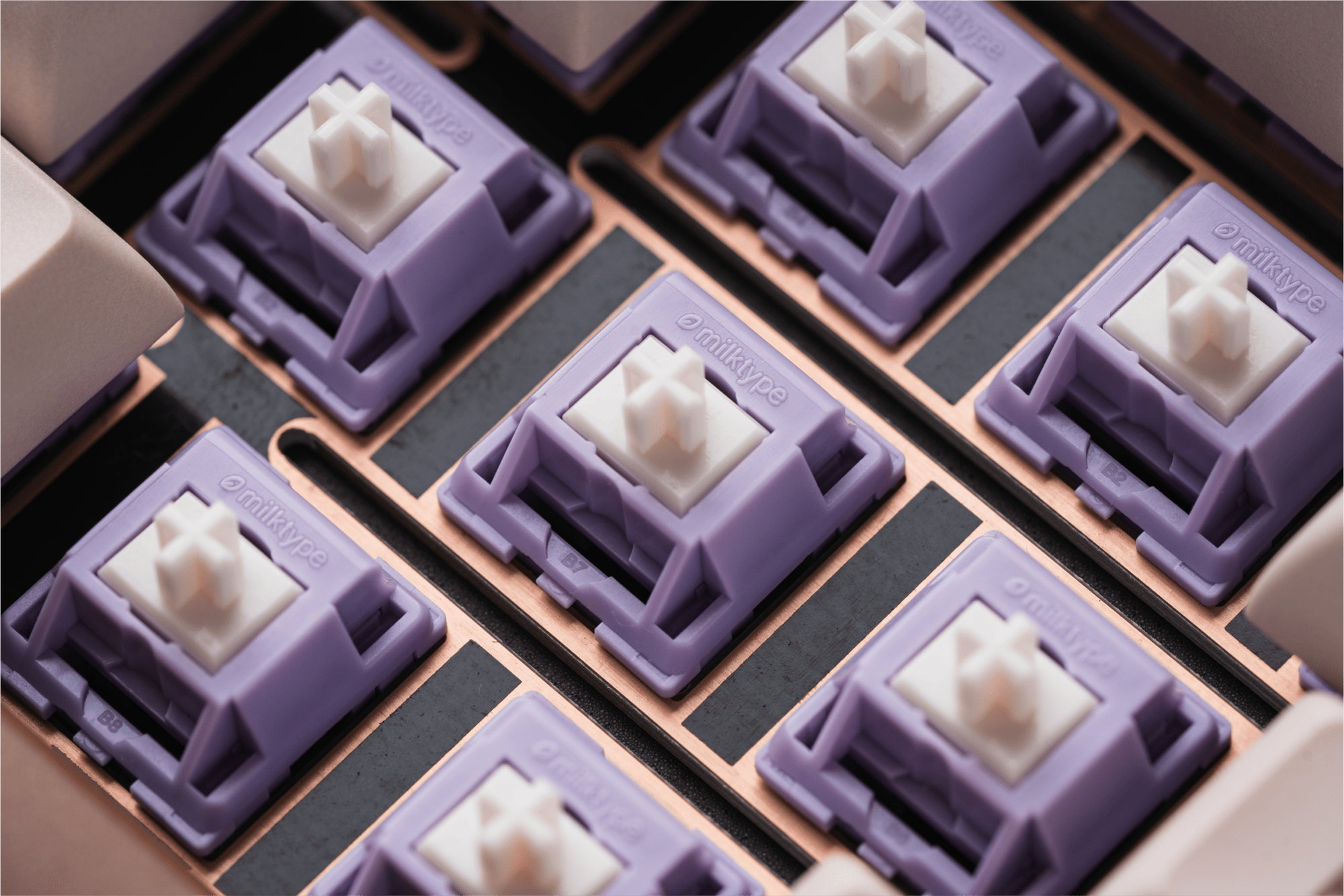 a close-up shot of the Taro switches on Sprout 75. they have a light purple housing with a subtle cream-colored stem, and the milktype logo is etched into the housing.